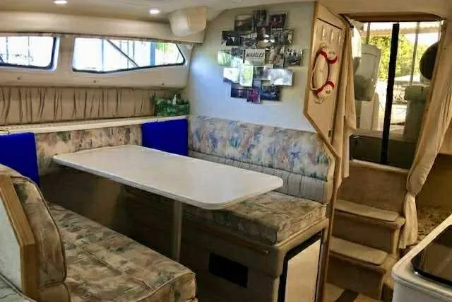 Slide: The Image of 1999 Bayliner 2855 Ciera interior with dining area, cushioned seating, and wall decor. - 2