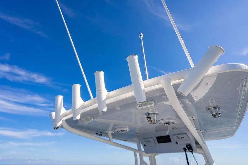 Slide: The Image of 2026 Reef Runner 230 boat top view with rod holders against blue sky. - 39