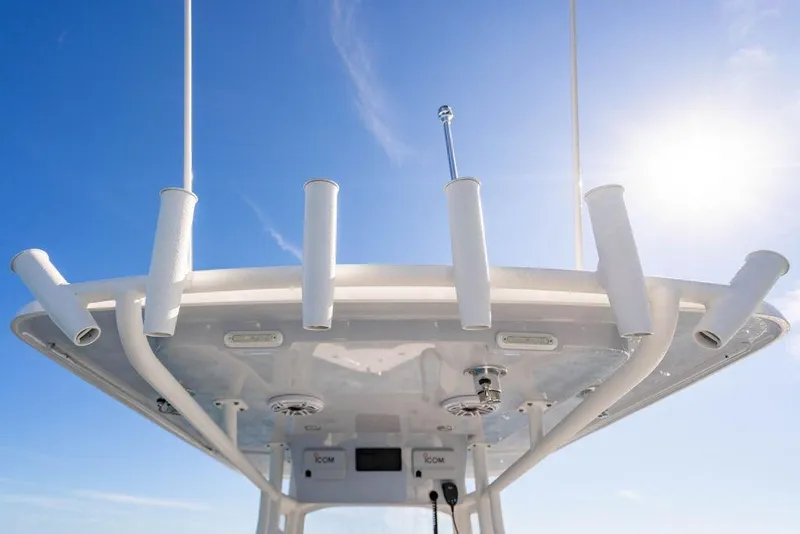 Slide: The Image of Reef Runner 230 boat roof with rod holders against clear blue sky, 2026 model. - 40