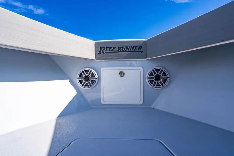 Slide: The Image of 2026 Reef Runner 230 boat interior with speakers and storage compartment under blue sky. - 48