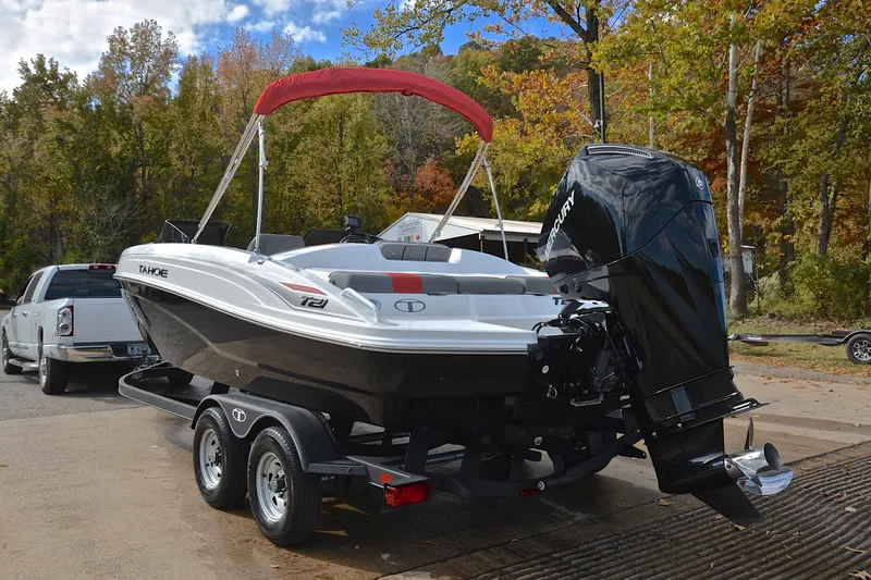 Slide: The Image of 2024 Tahoe T21 boat on trailer with outboard motor, parked near autumn trees. - 12