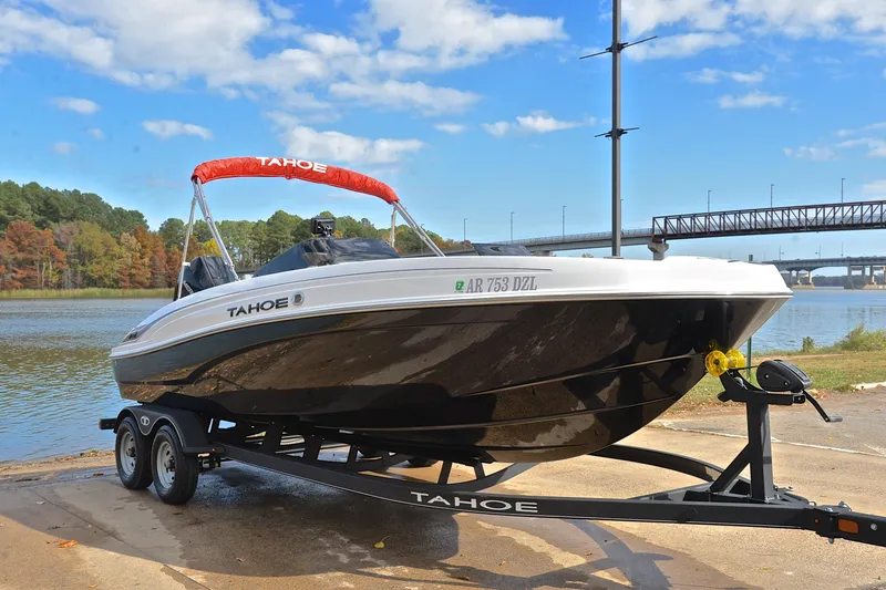 Slide: The Image of 2024 Tahoe T21 boat on trailer by a scenic river with bridge in background. - 16