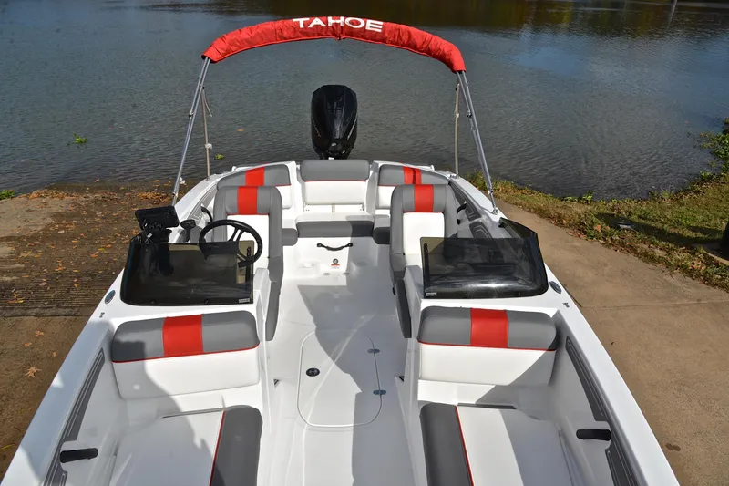 Slide: The Image of 2024 Tahoe T21 boat with red and gray seating, docked by a lake. - 20