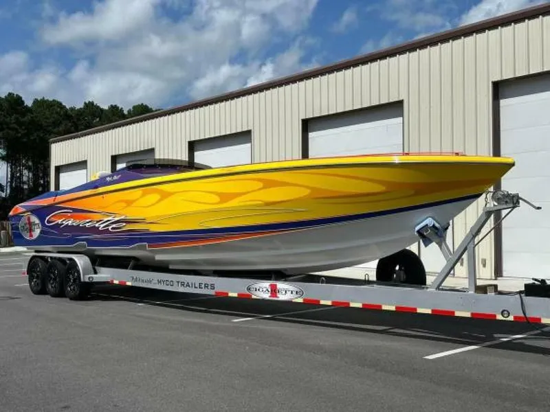The Image of 2005 Cigarette 39 Top Gun speedboat with vibrant yellow and orange design on a trailer. - 1
