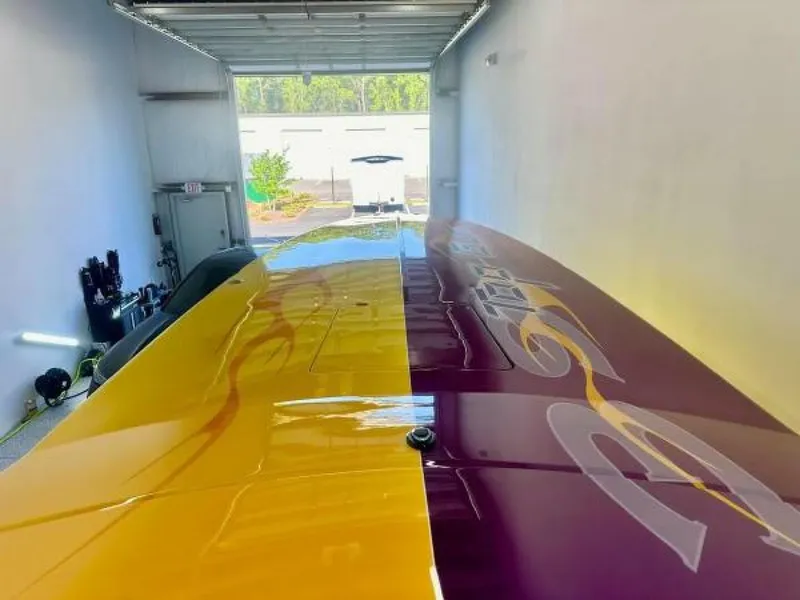 Slide: The Image of 2005 Cigarette 39 Top Gun boat with vibrant yellow and purple design in a garage. - 13