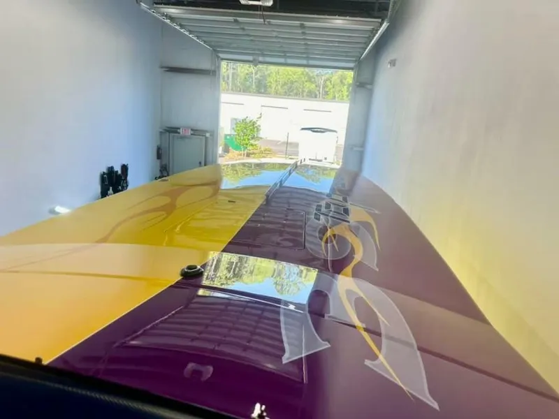 Slide: The Image of 2005 Cigarette 39 Top Gun boat with vibrant yellow and purple design in a garage. - 15