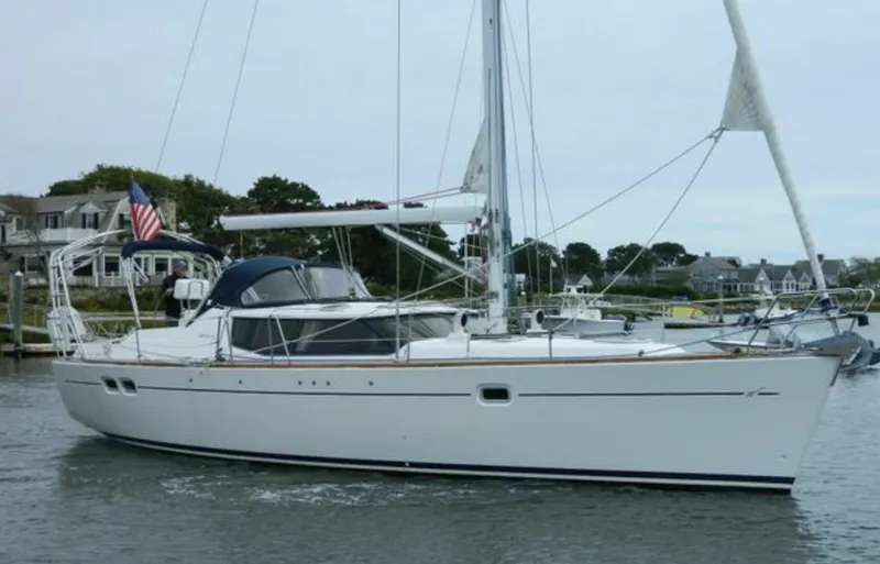 The Image of 2003 Wauquiez 40 Pilot Saloon sailboat on calm water near coastal homes. - 1