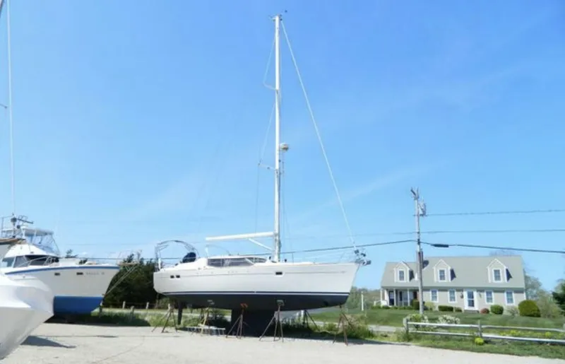 Slide: The Image of 2003 Wauquiez 40 Pilot Saloon sailboat on stands, clear sky, house in background. - 20