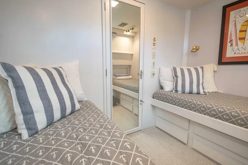 Slide: The Image of 1989 Hatteras Custom Cockpit cabin with twin beds, nautical decor, and striped pillows. - 40
