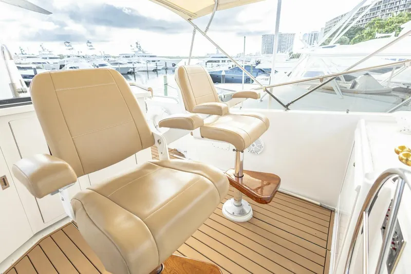 Slide: The Image of 1989 Hatteras Custom Cockpit with beige leather seats and wooden flooring, docked at marina. - 55