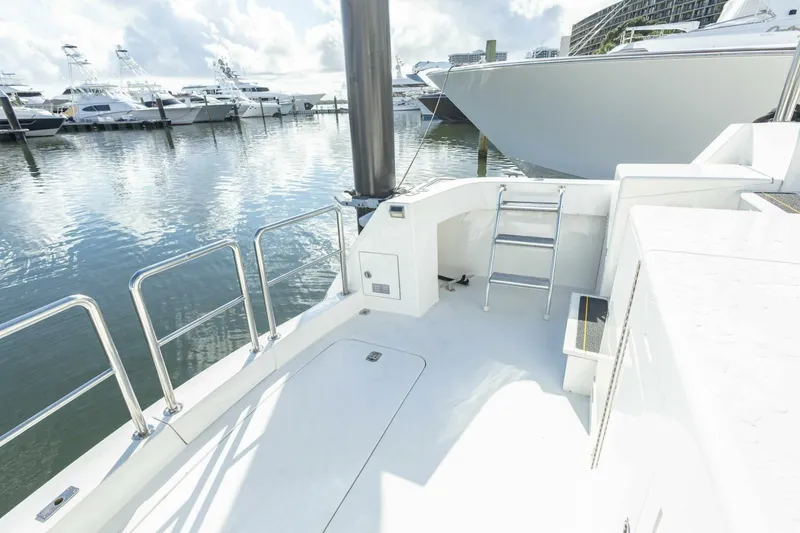 Slide: The Image of 1989 Hatteras Custom Cockpit yacht docked in marina, featuring sleek white design and stainless steel railings. - 61