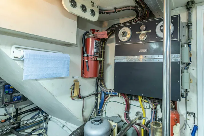 Slide: The Image of Engine room of 1989 Hatteras Custom Cockpit with control panel and fire extinguisher. - 69