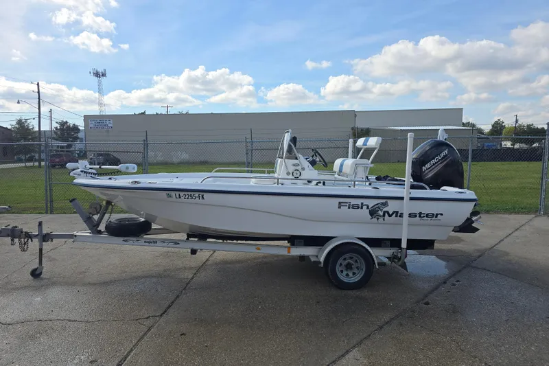 Slide: The Image of Fishmaster 1960 boat from 2004 on a trailer, parked outdoors under a cloudy sky. - 7
