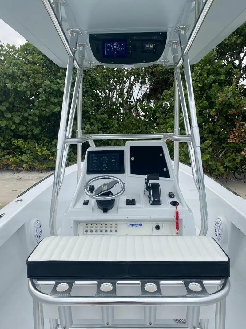 Slide: The Image of 1988 Intrepid 24 boat cockpit with steering wheel, controls, and seating, surrounded by lush greenery. - 4