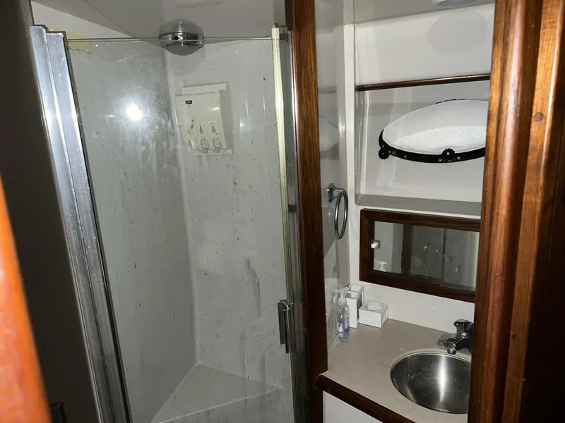 Slide: The Image of 1987 Californian 42 Motor Yacht bathroom with shower, sink, mirror, and wooden accents. - 15