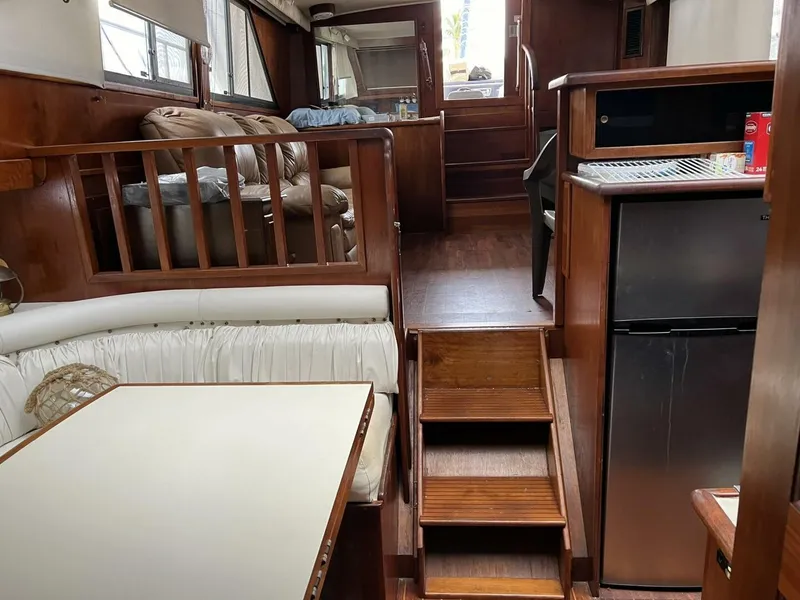 Slide: The Image of 1987 Californian 42 Motor Yacht interior with wood finish, seating area, and compact kitchen. - 18