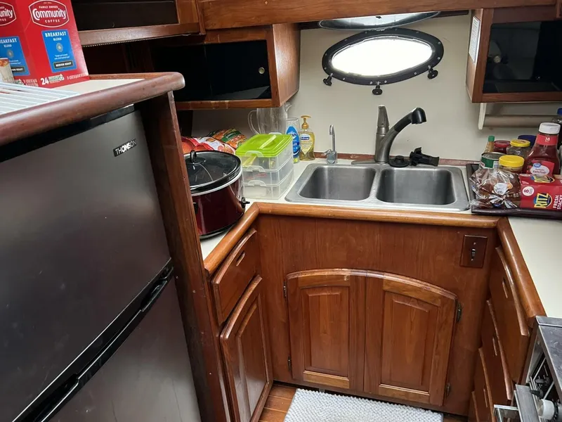 Slide: The Image of 1987 Californian 42 Motor Yacht kitchen with wooden cabinets, double sink, and compact fridge. - 9