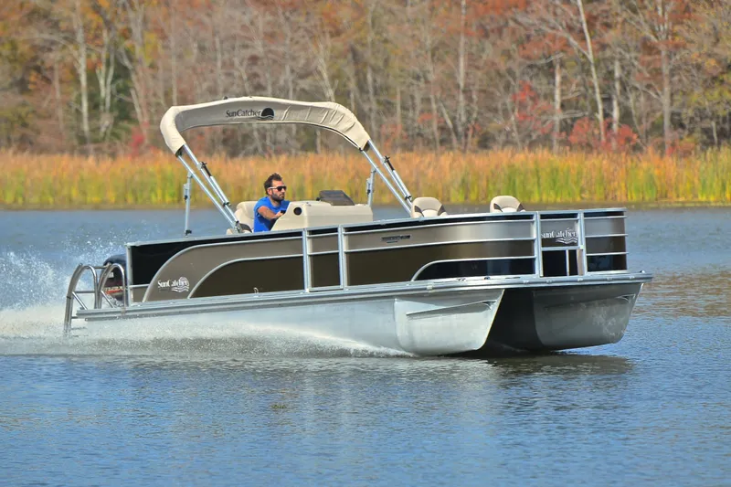 The Image of 2023 SunCatcher Select 22F pontoon boat cruising on a scenic lake. - 1
