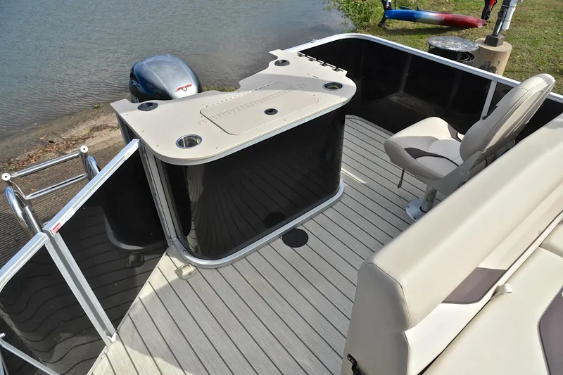 Slide: The Image of 2023 SunCatcher Select 22F pontoon boat interior with seating and helm, docked by the water. - 24