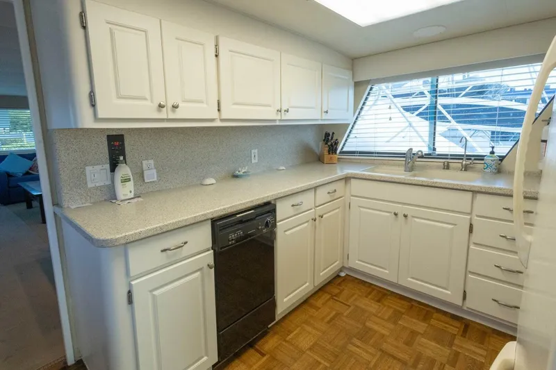 Slide: The Image of Kitchen interior of 1987 Hatteras 70 Cockpit Motor Yacht with white cabinets and large window. - 13