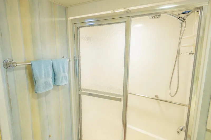 Slide: The Image of Bathroom with glass shower door and blue towels on a 1987 Hatteras 70 Cockpit Motor Yacht. - 23