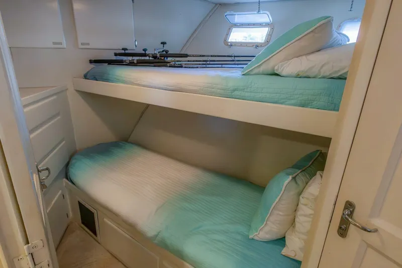 Slide: The Image of Bunk beds in 1987 Hatteras 70 Cockpit Motor Yacht cabin with fishing rods and teal bedding. - 25