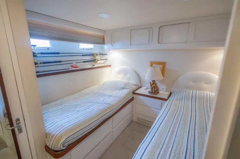 Slide: The Image of 1987 Hatteras 70 Cockpit Motor Yacht cabin with twin beds and fishing rods. - 28