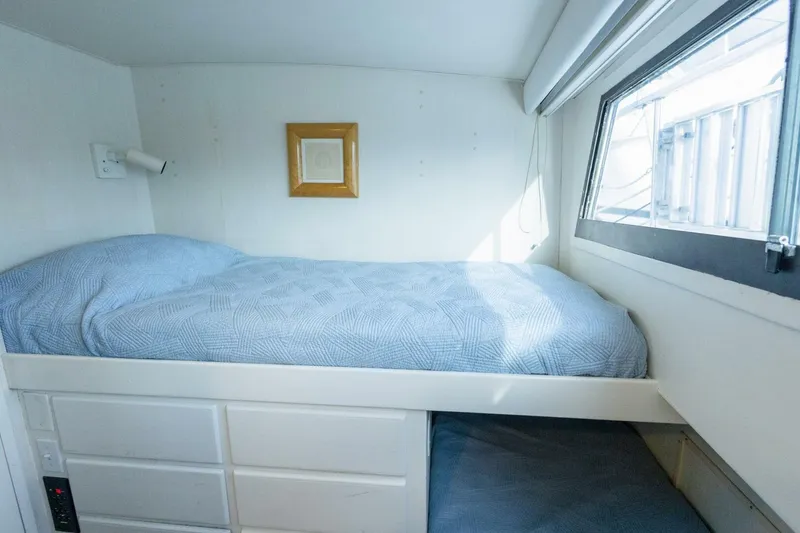 Slide: The Image of Cozy cabin bed in 1987 Hatteras 70 Cockpit Motor Yacht with blue bedding and window. - 30