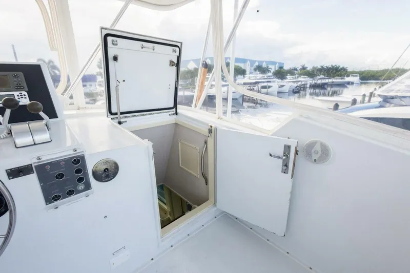 Slide: The Image of 1987 Hatteras 70 Cockpit Motor Yacht helm with open hatch and marina view. - 33