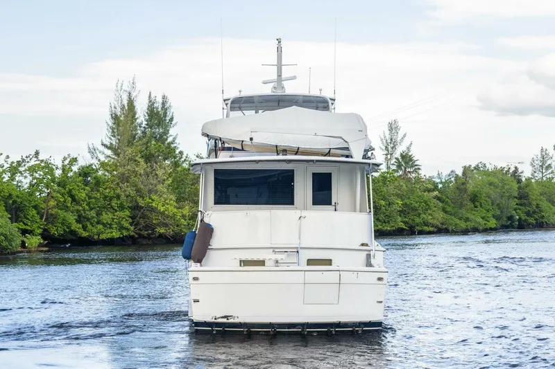 Slide: The Image of 1987 Hatteras 70 Cockpit Motor Yacht on a serene waterway, surrounded by lush greenery. - 41