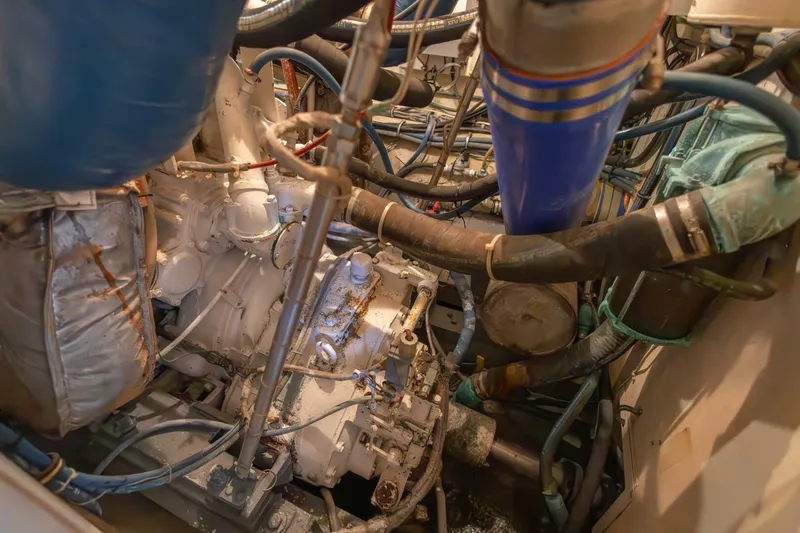 Slide: The Image of Engine room of 1987 Hatteras 70 Cockpit Motor Yacht with complex machinery and hoses. - 44