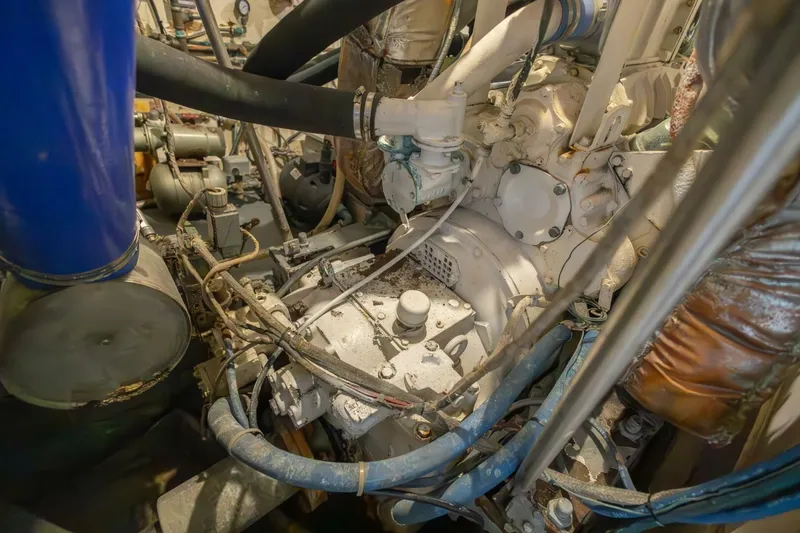 Slide: The Image of Engine room of 1987 Hatteras 70 Cockpit Motor Yacht with visible machinery and hoses. - 48
