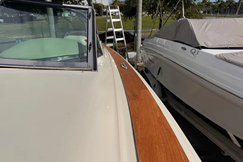 Slide: The Image of 2014 Chris-Craft Launch 28 boat with wooden trim, parked beside another covered boat. - 21