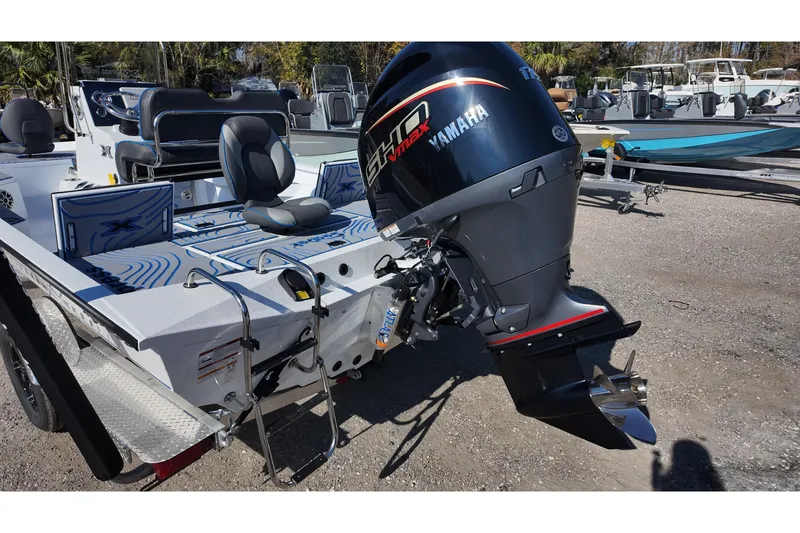 Slide: The Image of 2026 Xpress H22B Bay boat with Yamaha outboard motor, parked on gravel. - 15