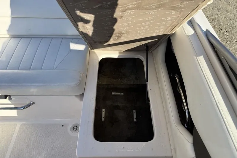 Slide: The Image of Open storage compartment in a 2006 Regal 2000 boat, featuring white seating and metal handle. - 17