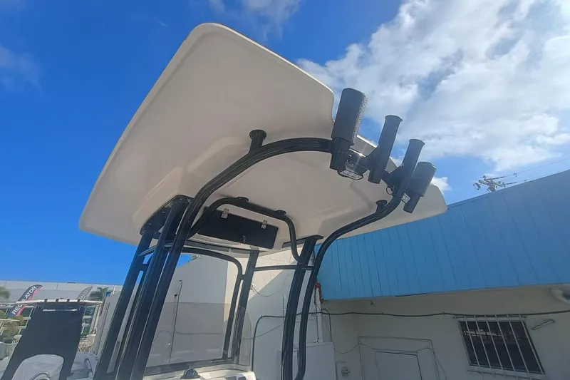 Slide: The Image of 2026 Robalo R222 Center Console boat with T-top and rod holders under a blue sky. - 26