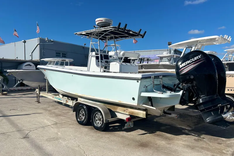 Slide: The Image of 1991 Contender 25 Open boat on trailer with Mercury outboard motor, docked outdoors. - 2