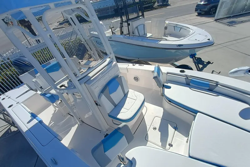 Slide: The Image of 2026 Robalo 226 Cayman boat with blue and white seating, docked outdoors. - 18