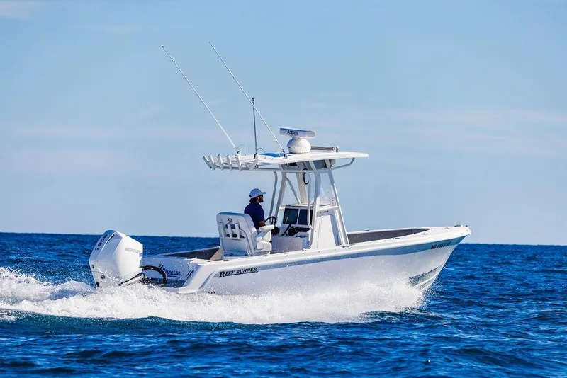 Slide: The Image of 2026 Reef Runner 230 boat dashboard with dual screens and steering wheel on open water. - 21