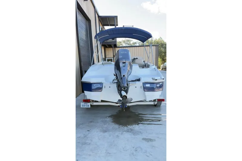 Slide: The Image of 2013 NauticStar 203 SC boat with outboard motor and blue canopy, parked outside. - 4