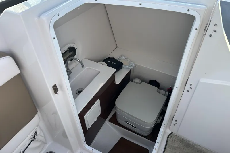 Slide: The Image of 2016 Four Winns HD270 OB boat interior with compact bathroom and sink. - 8