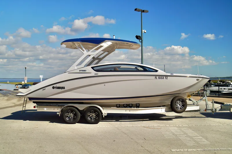 Slide: The Image of 2025 Yamaha Boats 275SD on trailer at marina, under clear blue sky. - 1