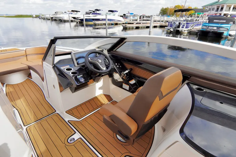 Slide: The Image of 2025 Yamaha Boats 275SD cockpit with modern steering and luxurious seating at a marina. - 15