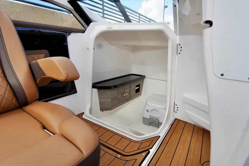 Slide: The Image of 2025 Yamaha Boats 275SD interior cabin with seating and compact restroom. - 19