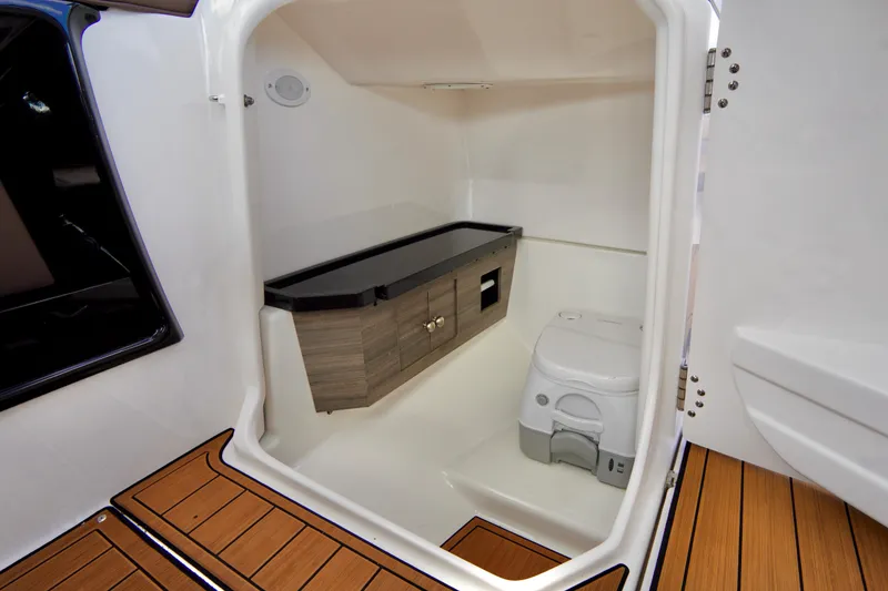 Slide: The Image of Interior of 2025 Yamaha Boats 275SD, featuring a compact marine bathroom with wooden flooring. - 20