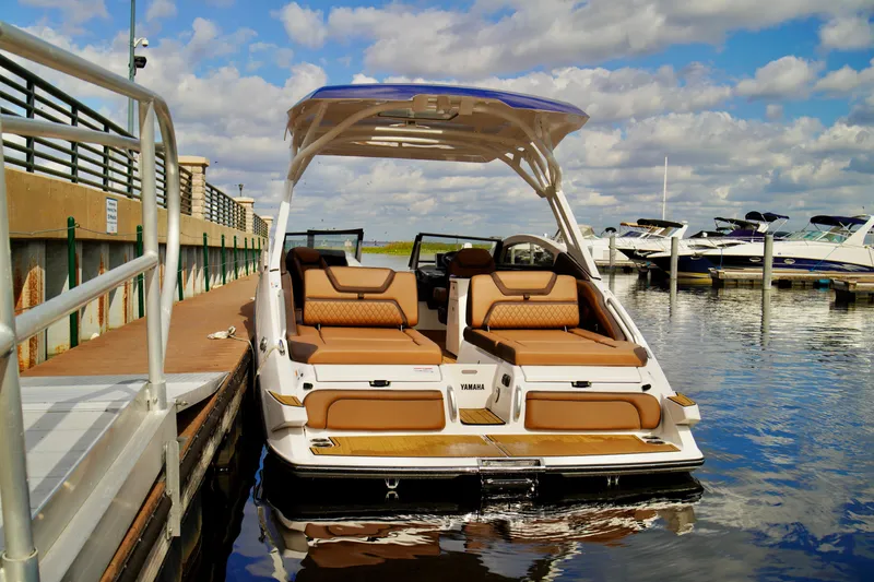 Slide: The Image of 2025 Yamaha Boats 275SD docked, showcasing luxurious seating and sleek design under a blue sky. - 28