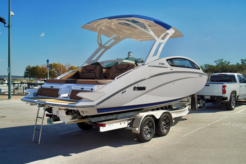 Slide: The Image of 2025 Yamaha Boats 275SD on trailer, parked at marina under clear blue sky. - 30