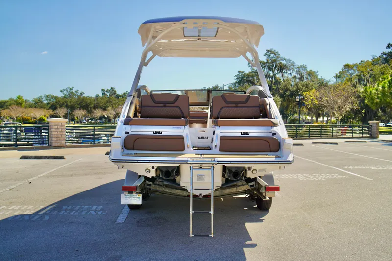 Slide: The Image of 2025 Yamaha Boats 275SD in parking lot, rear view with seating and ladder. - 31