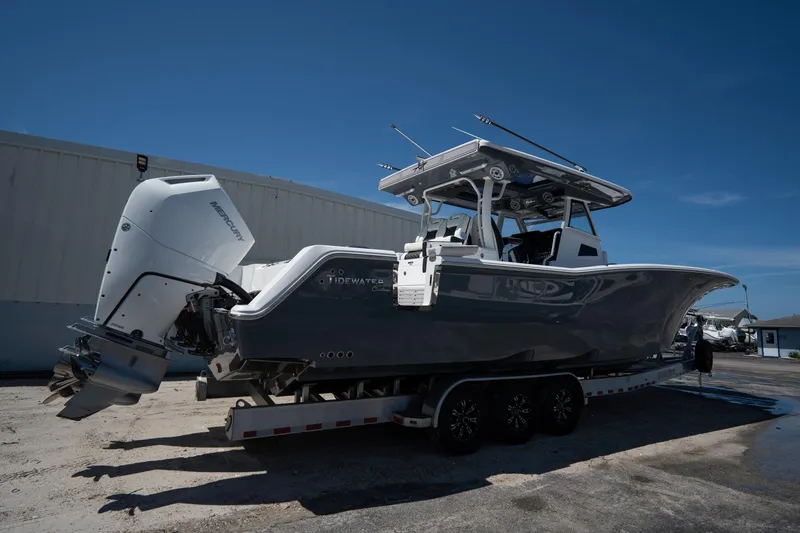 Slide: The Image of 2023 Tidewater 380 CC Adventure boat docked near waterfront homes and palm trees. - 2