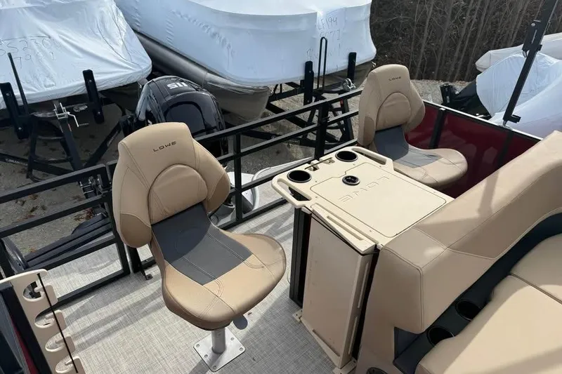 Slide: The Image of 2026 Lowe LF 214 boat interior with beige seating and table, parked outdoors. - 10